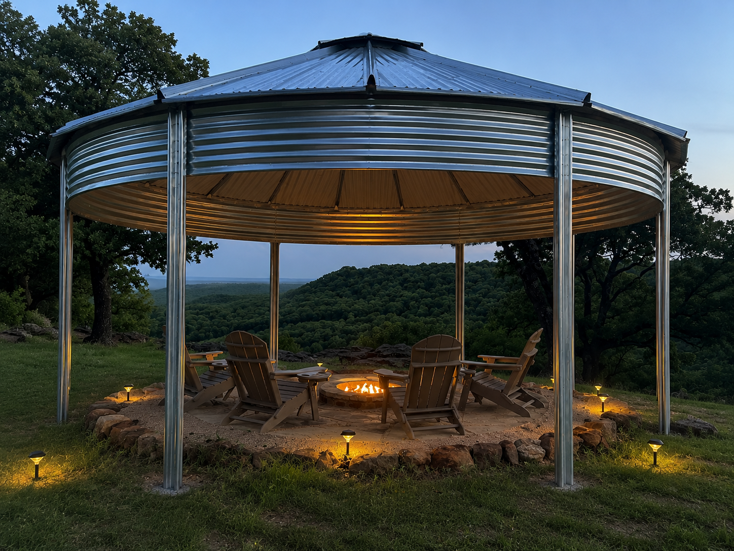 Binzebo on a hilltop at dusk overlooking forested ridges with a stone fire pit